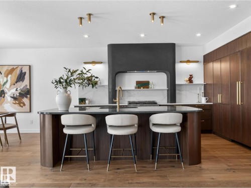 Modern kitchen island with fluted wood-finish paneling and a dark countertop - 7104 54 Avenue, Beaumont, AB - Indoor Photo Showing Other Room