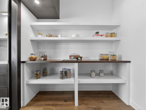 White built-in shelving with a dark wood-finish countertop - 7104 54 Avenue, Beaumont, AB - Indoor With Storage