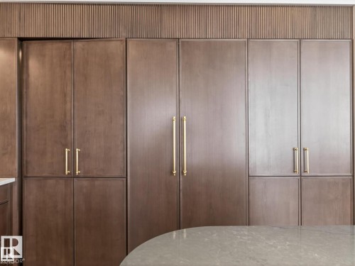 Built-in cabinetry featuring rich wood-finish panels and brass hardware - 7104 54 Avenue, Beaumont, AB - Indoor