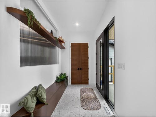 Entryway featuring light-toned irregular tile flooring, a built-in wood bench, and a fluted privacy window - 7104 54 Avenue, Beaumont, AB - Indoor Photo Showing Other Room