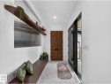 Entryway featuring light-toned irregular tile flooring, a built-in wood bench, and a fluted privacy window - 7104 54 Avenue, Beaumont, AB  - Indoor Photo Showing Other Room 