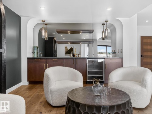 Built-in wet bar featuring dark wood-finish cabinetry, a beverage refrigerator, and a mirrored backsplash - 7104 54 Avenue, Beaumont, AB - Indoor