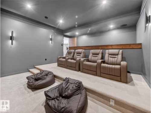 Dedicated home theater space featuring tiered carpeted flooring, gray walls, recessed lighting, and wall-mounted sconces - 7104 54 Avenue, Beaumont, AB - Indoor