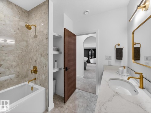 Bathroom featuring a white soaking tub with brass fixtures, a quartz countertop vanity with integrated sink, and a framed mirror - 7104 54 Avenue, Beaumont, AB - Indoor Photo Showing Bathroom