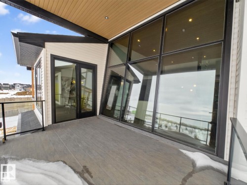 Expansive outdoor deck featuring wood-finish flooring and glass panel railings - 7104 54 Avenue, Beaumont, AB - Outdoor With Exterior