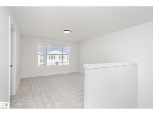 Bright, open interior space with light-colored patterned carpeting and white walls - 6302 Dansereau Crescent, Beaumont, AB - Indoor Photo Showing Other Room