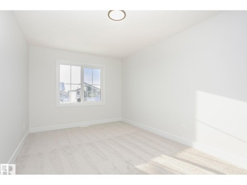 Bright room featuring light-toned carpeting, white walls, and a large window with white trim - 6302 Dansereau Crescent, Beaumont, AB - Indoor Photo Showing Other Room