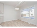 Bright interior space featuring light wood-finish flooring, white baseboards, and a large window with white framing - 6302 Dansereau Crescent, Beaumont, AB  - Indoor Photo Showing Other Room 
