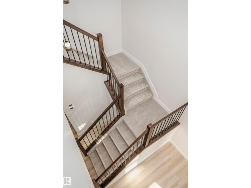 Contemporary staircase featuring wood-finish handrails and black metal balusters - 6302 Dansereau Crescent, Beaumont, AB - Indoor Photo Showing Other Room