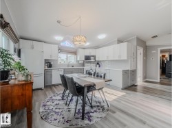 Kitchen featuring two-tone cabinetry with white upper and gray lower cabinets, white subway tile backsplash, and light wood-finish flooring - 