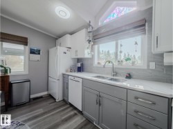 Modern kitchen featuring two-tone cabinetry, white countertops, and a subway tile backsplash - 