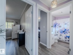 Hallway featuring wood-finish flooring, white baseboards, and a decorative ceiling light fixture - 