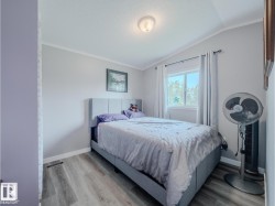 Bedroom featuring wood-finish flooring, a window with natural light, a ceiling-mounted light fixture, and crown molding - 