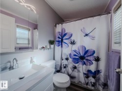 Bathroom featuring a modern rectangular vessel sink, polished chrome faucet, white vanity with cabinet storage, and a large wall-mounted mirror with integrated lighting - 