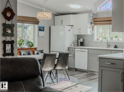 Modern kitchen and dining area with dual-tone cabinetry, wood-finish flooring, and a patterned backsplash - 