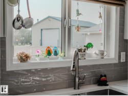 Kitchen window with a stainless steel pull-down faucet, undermount sink, and light-toned solid surface countertop - 