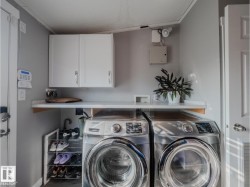Dedicated laundry area featuring a built-in counter, upper white cabinetry, and a utility sink - 