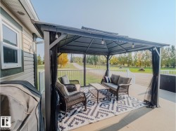 Patio featuring a permanent gazebo with string lighting, a concrete surface, and white railing - 