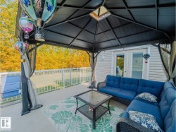Outdoor deck featuring a dark gazebo with a skylight, privacy curtains, and a white railing system - 