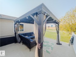 Concrete patio featuring a dark-framed gazebo with sheer curtains, string lighting, and a white railing - 