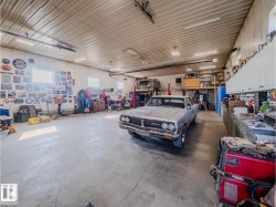 Spacious garage featuring a concrete floor, corrugated metal ceiling, high windows, and fluorescent lighting - 