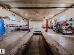 Spacious garage featuring a concrete floor, overhead lighting, multiple windows, extensive built-in cabinetry, and a large overhead door - 