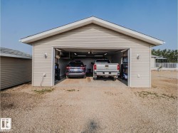 Detached garage featuring light-colored siding, a gabled roofline, and a wide entryway - 