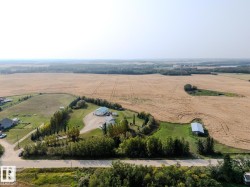 Expansive agricultural property featuring a primary residence, a large outbuilding with a green roof, and a separate barn with a metal roof - 