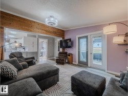 Living area featuring light wood-finish flooring, a wood-paneled accent wall, and a contemporary ceiling fixture - 