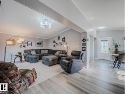 Open-concept living area featuring light wood-finish flooring, a contemporary ceiling fan, and crisp white trim - 