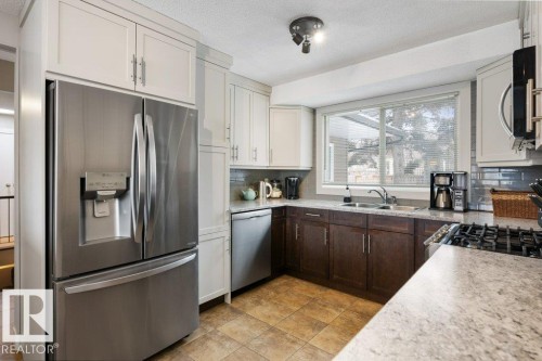 The kitchen features a stainless steel refrigerator, a gas cooktop, and a window above the sink - 7 Ash Place, St. Albert, AB - Indoor Photo Showing Kitchen With Stainless Steel Kitchen With Double Sink