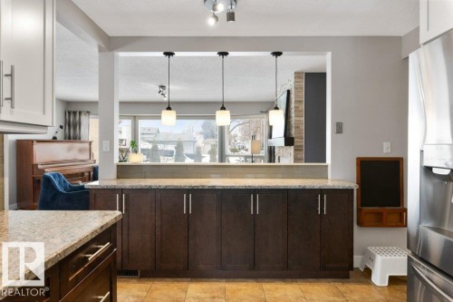The kitchen features a tiled floor, dark wood cabinetry with silver handles, and granite countertops - 7 Ash Place, St. Albert, AB - Indoor Photo Showing Kitchen With Upgraded Kitchen