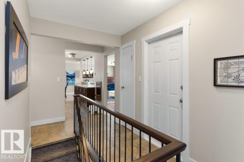 The property features a staircase with dark wood railings and black metal spindles, leading to a tiled landing - 7 Ash Place, St. Albert, AB - Indoor Photo Showing Other Room