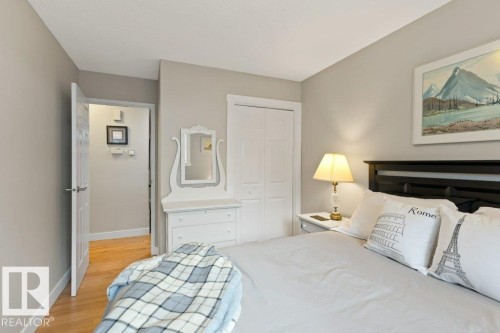 This bedroom features neutral-toned walls, hardwood floors, and a built-in closet with bi-fold doors - 7 Ash Place, St. Albert, AB - Indoor Photo Showing Bedroom