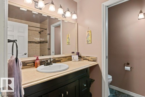 The bathroom features a vanity with a light-colored countertop and an oval sink, illuminated by a four-bulb light fixture - 7 Ash Place, St. Albert, AB - Indoor Photo Showing Bathroom
