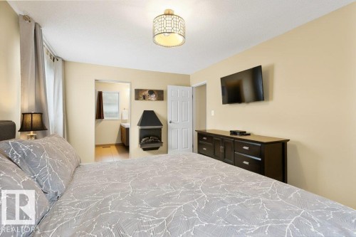 Spacious room featuring light-colored walls, a ceiling-mounted light fixture, and a built-in corner fireplace - 7 Ash Place, St. Albert, AB - Indoor Photo Showing Bedroom