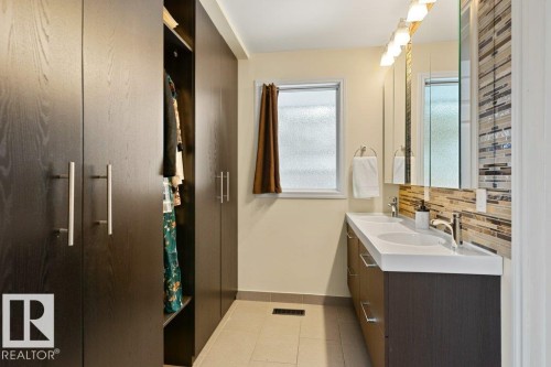 Bathroom featuring a double vanity with an integrated white countertop, a mosaic tile backsplash, and a window providing natural light - 7 Ash Place, St. Albert, AB - Indoor Photo Showing Bathroom