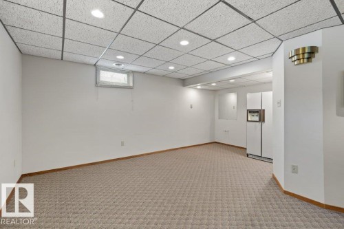 Spacious room featuring patterned carpet flooring, white walls, and a drop ceiling with recessed lighting - 7 Ash Place, St. Albert, AB - Indoor Photo Showing Other Room