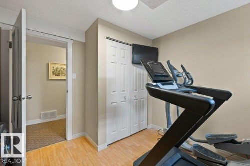 The property features a room with light wood flooring, neutral-toned walls, and a closet with white bi-fold doors - 7 Ash Place, St. Albert, AB - Indoor