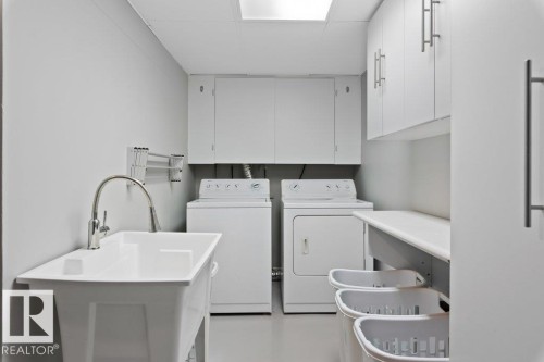 The laundry room features a utility sink with a gooseneck faucet, a washer and dryer, and white cabinetry - 7 Ash Place, St. Albert, AB - Indoor Photo Showing Laundry Room
