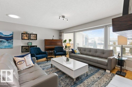 Spacious living area featuring large windows providing natural light, hardwood floors, and a ceiling light fixture - 7 Ash Place, St. Albert, AB - Indoor Photo Showing Living Room