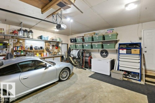 Spacious garage featuring concrete flooring, built-in shelving, and a workshop area with a workbench - 7 Ash Place, St. Albert, AB - Indoor Photo Showing Garage