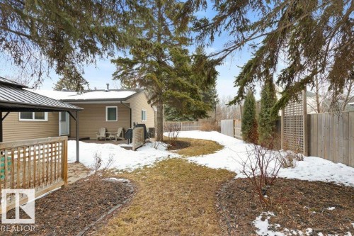 The property features a fenced yard with established trees and a paved patio area - 7 Ash Place, St. Albert, AB - Outdoor