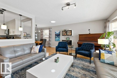 The property features an open-concept living area with light hardwood floors and a partial wall dividing the kitchen - 7 Ash Place, St. Albert, AB - Indoor Photo Showing Living Room