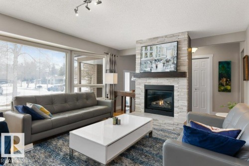 Living room featuring a fireplace with a stone surround and a substantial wood mantel - 7 Ash Place, St. Albert, AB - Indoor Photo Showing Living Room With Fireplace