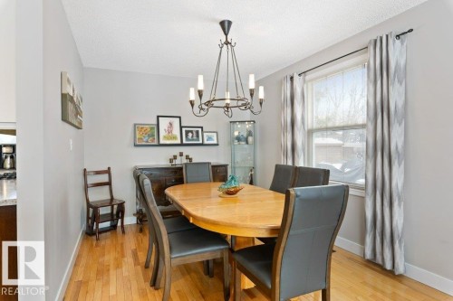 Dining area featuring hardwood floors, a window with curtains, and a chandelier - 7 Ash Place, St. Albert, AB - Indoor Photo Showing Dining Room