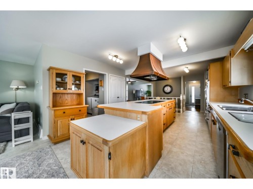 Kitchen featuring wood cabinetry, white countertops, a copper-toned range hood, built-in appliances, and tile flooring - 10231 46 Street, Edmonton, AB 