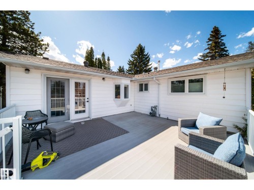 Spacious outdoor deck featuring light-toned composite decking, white railing, and a white siding exterior - 10231 46 Street, Edmonton, AB 