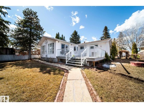 White-sided exterior featuring multiple windows and a sunroom extension - 10231 46 Street, Edmonton, AB 