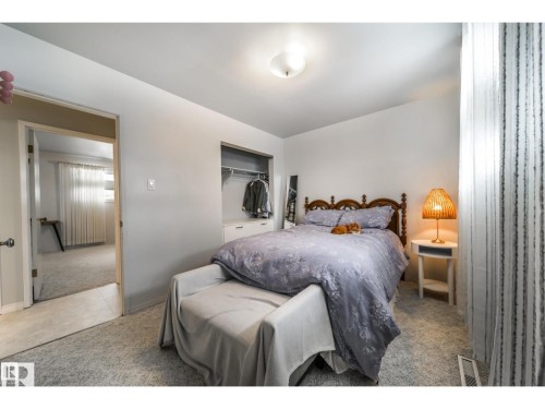 Carpeted bedroom with a built-in closet featuring shelving and hanging space - 10231 46 Street, Edmonton, AB 